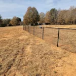 a fence in a field with trees in the background