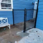 a fenced in area next to a blue house