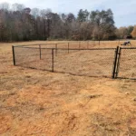 a fenced in area with trees in the background